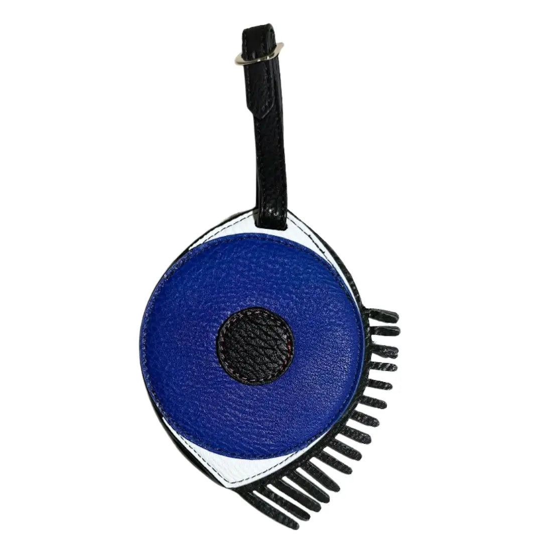 A circular blue and black eye-shaped leather bag charm or luggage tag with a black strap, shown on a plain white background.