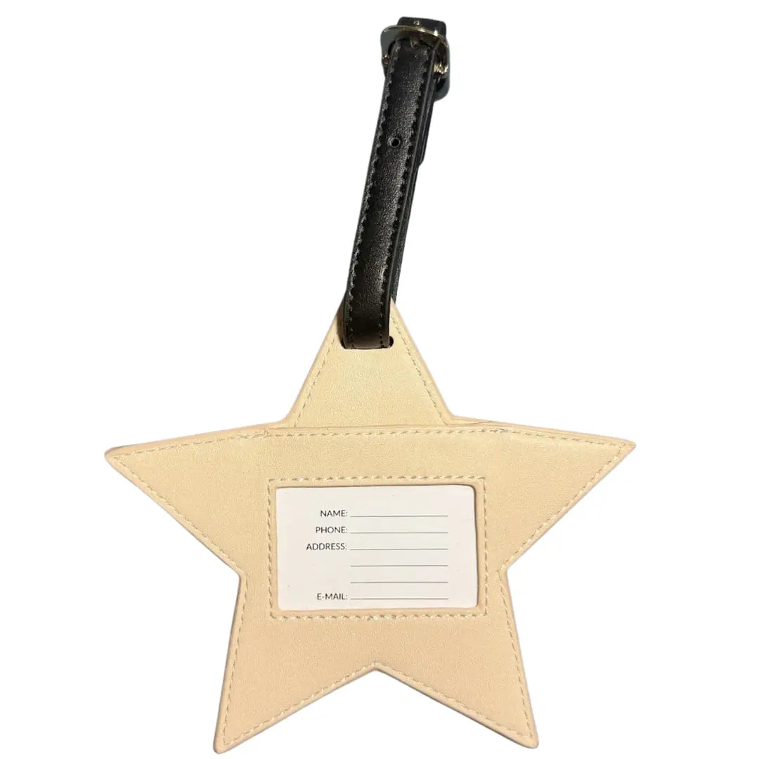 A star-shaped beige luggage tag with a black leather strap and a blank white name label in the center, shown on a plain white background.