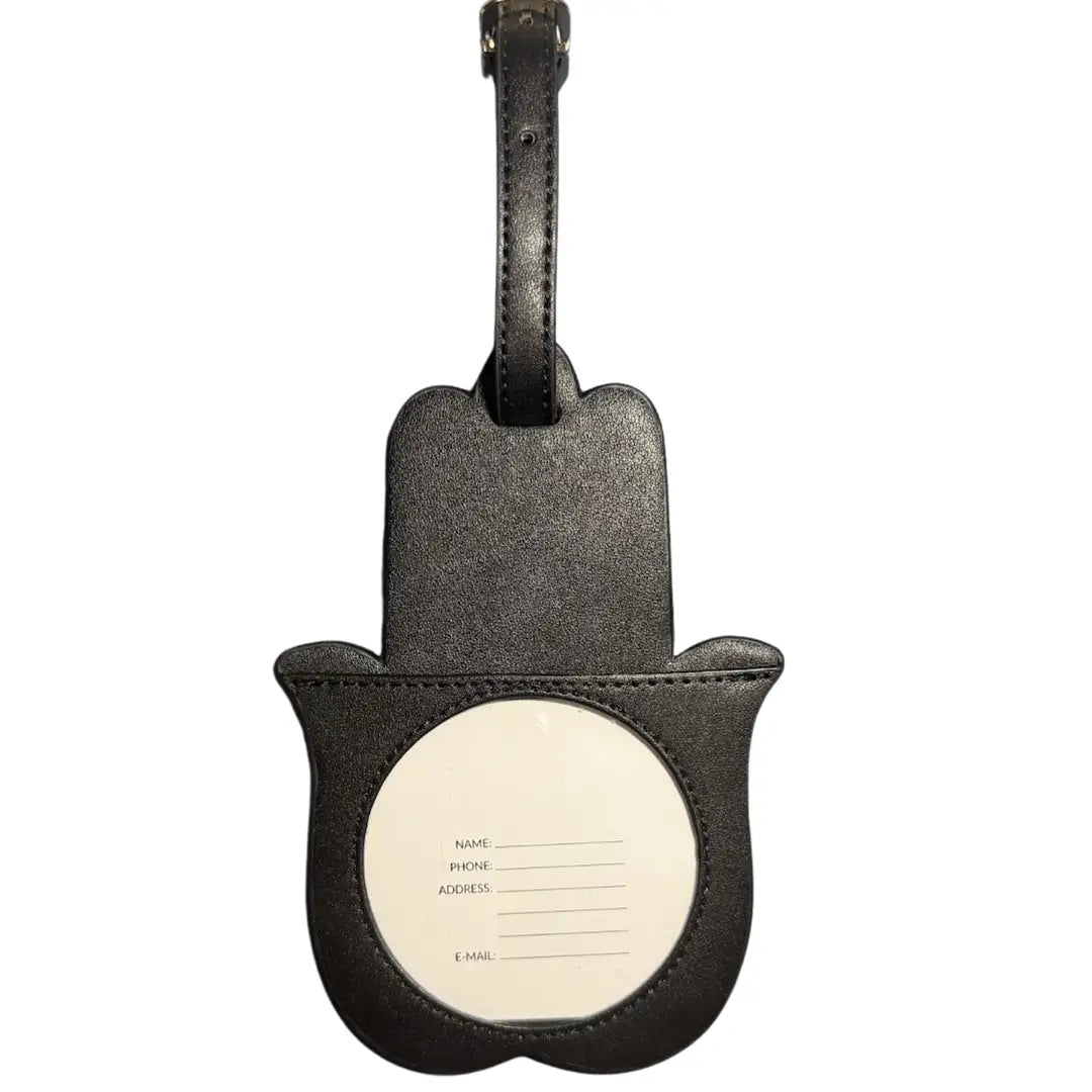 Black leather hamsa hand luggage tag with a white circular insert card for name, phone, address, and email details, shown on a plain white background.