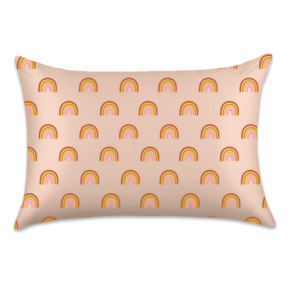 Rainbow satin pillowcase featuring small orange, yellow, and pink rainbows on a pale peach background.