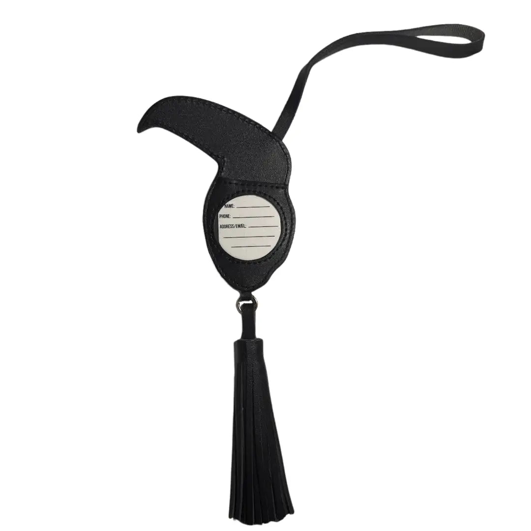 A black toucan luggage tag with a curved wing-like top, a central oval label, and a long black tassel, shown on a plain white background.