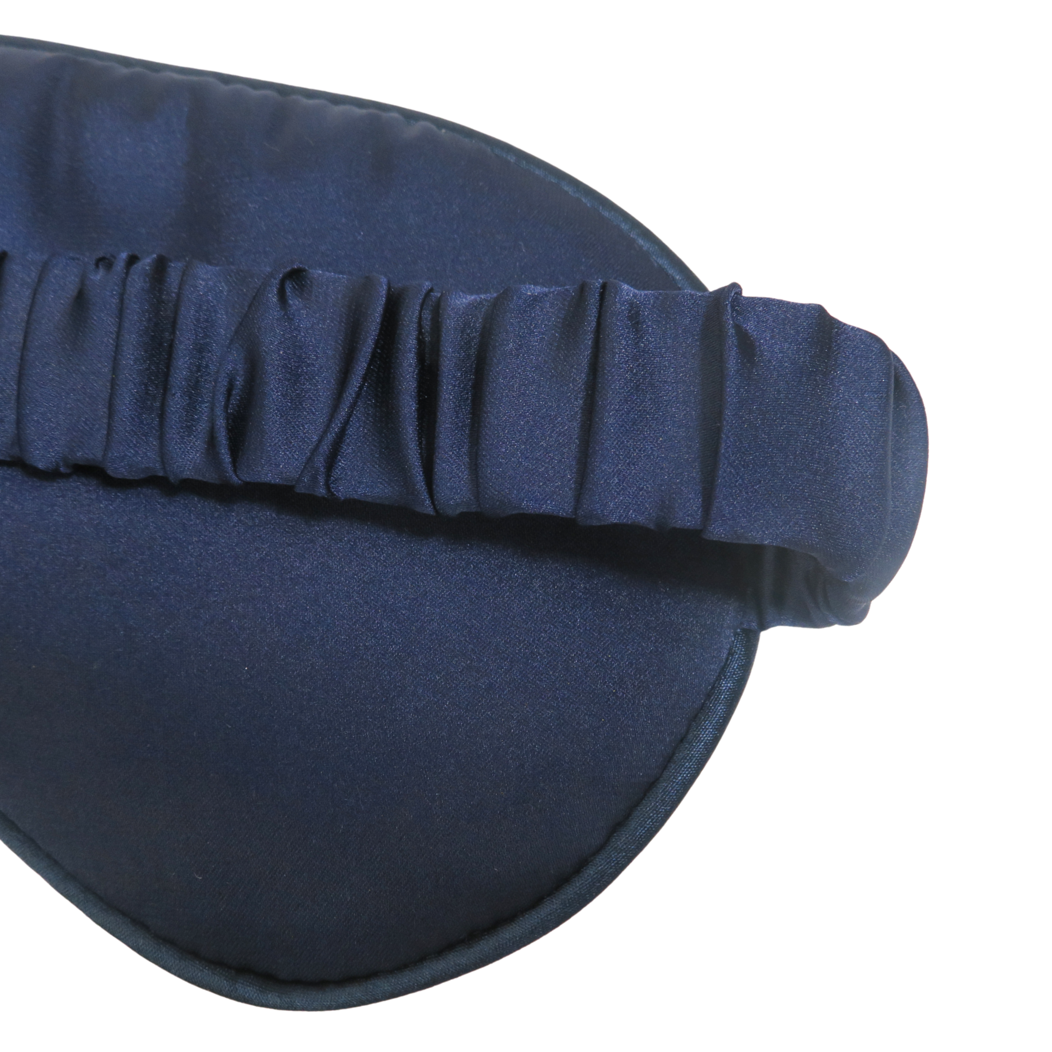 Close-up of a dark navy blue satin sleep mask with a ruched elastic strap, shown against a plain white background.