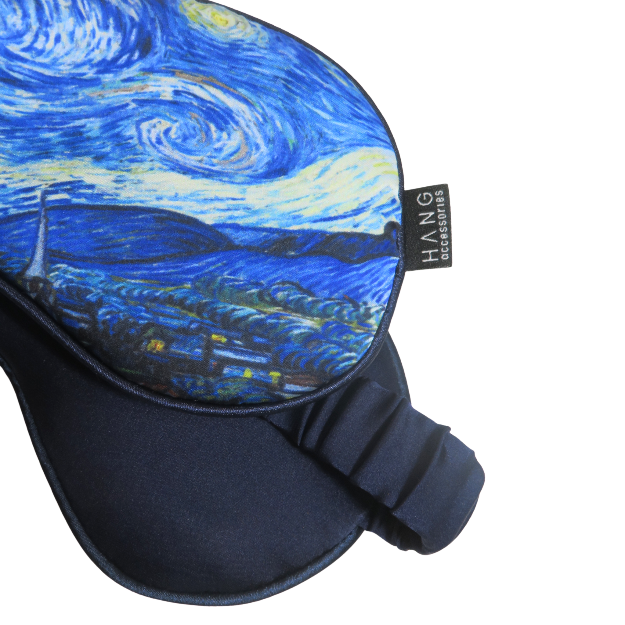 Front and back views of a blue and yellow swirling landscape sleep mask, showing the printed exterior and solid navy satin backing.