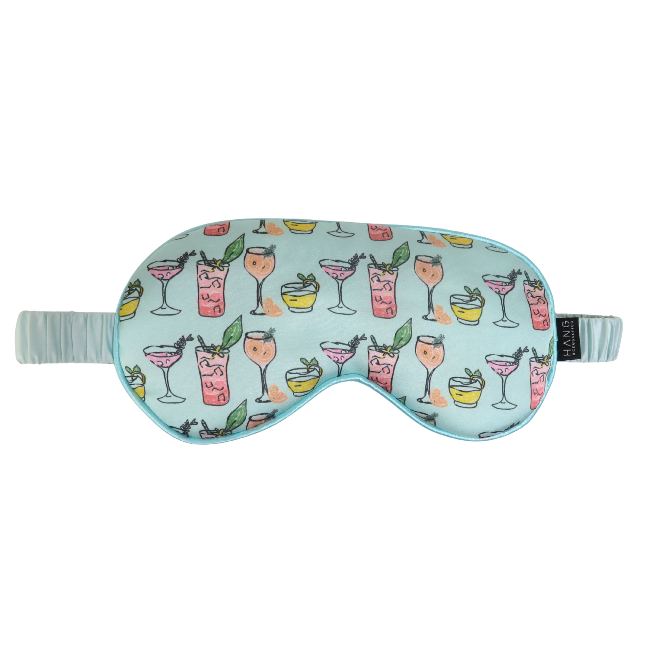 A light blue sleep mask with a repeating pattern of colorful cocktail glasses, featuring a matching elastic strap and a small black brand tag on the side.