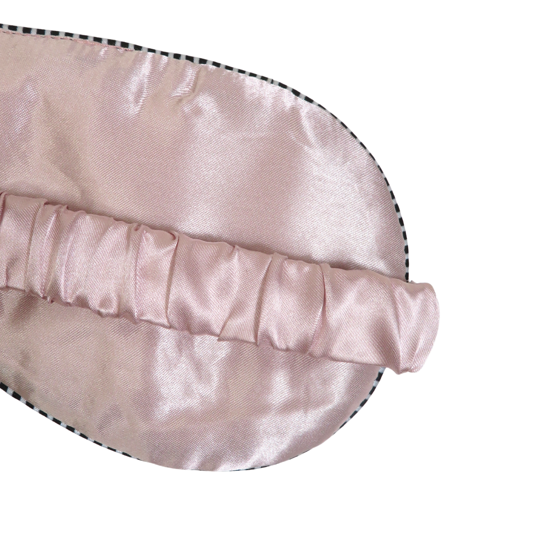A close-up of a light pink satin sleep mask with a ruched elastic strap, shown on a plain white background.