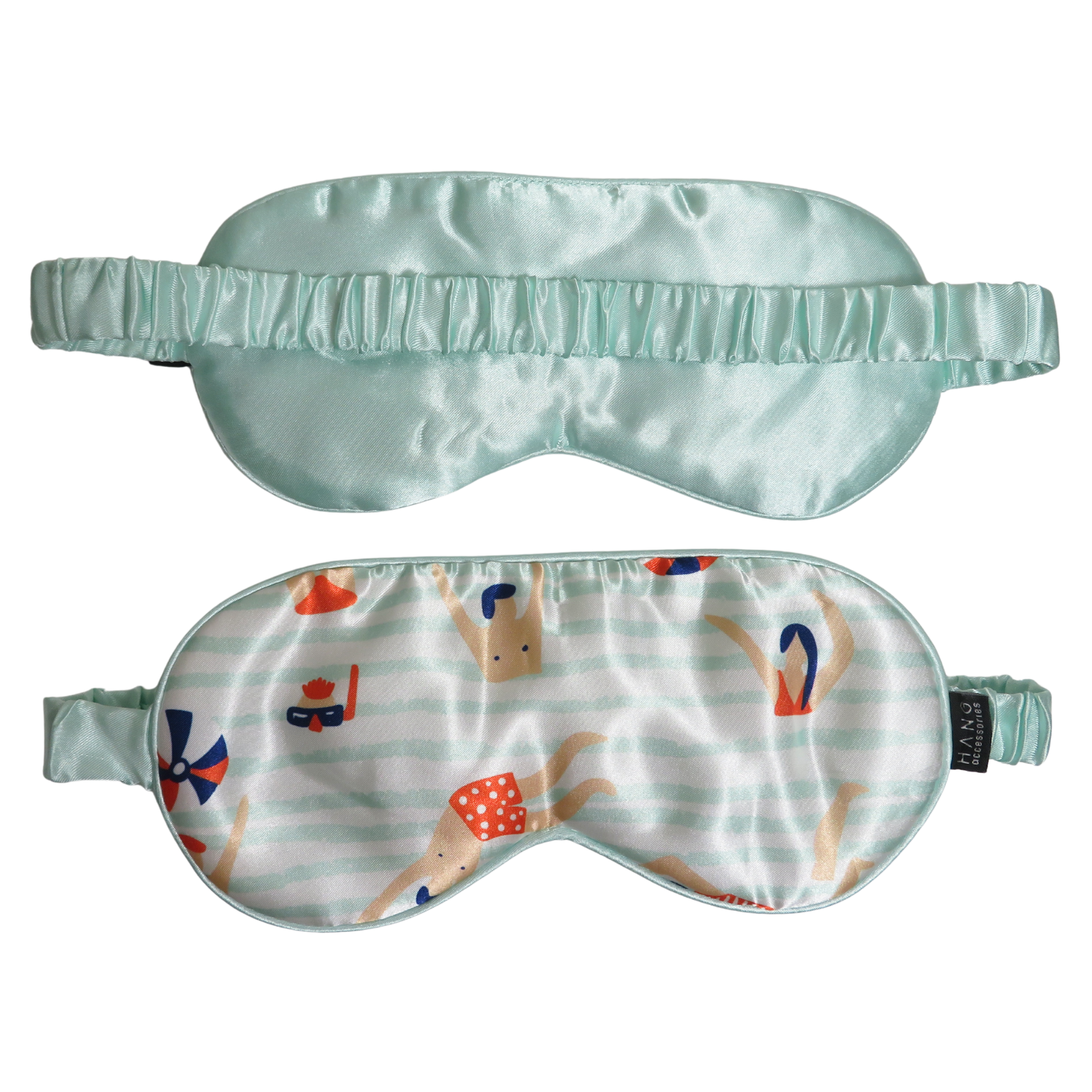 Two satin sleep masks shown on a plain white background: one in solid pale mint green and one with a white striped background and a playful print of cartoon figures in red, blue, and tan, plus matching mint green elastic straps.