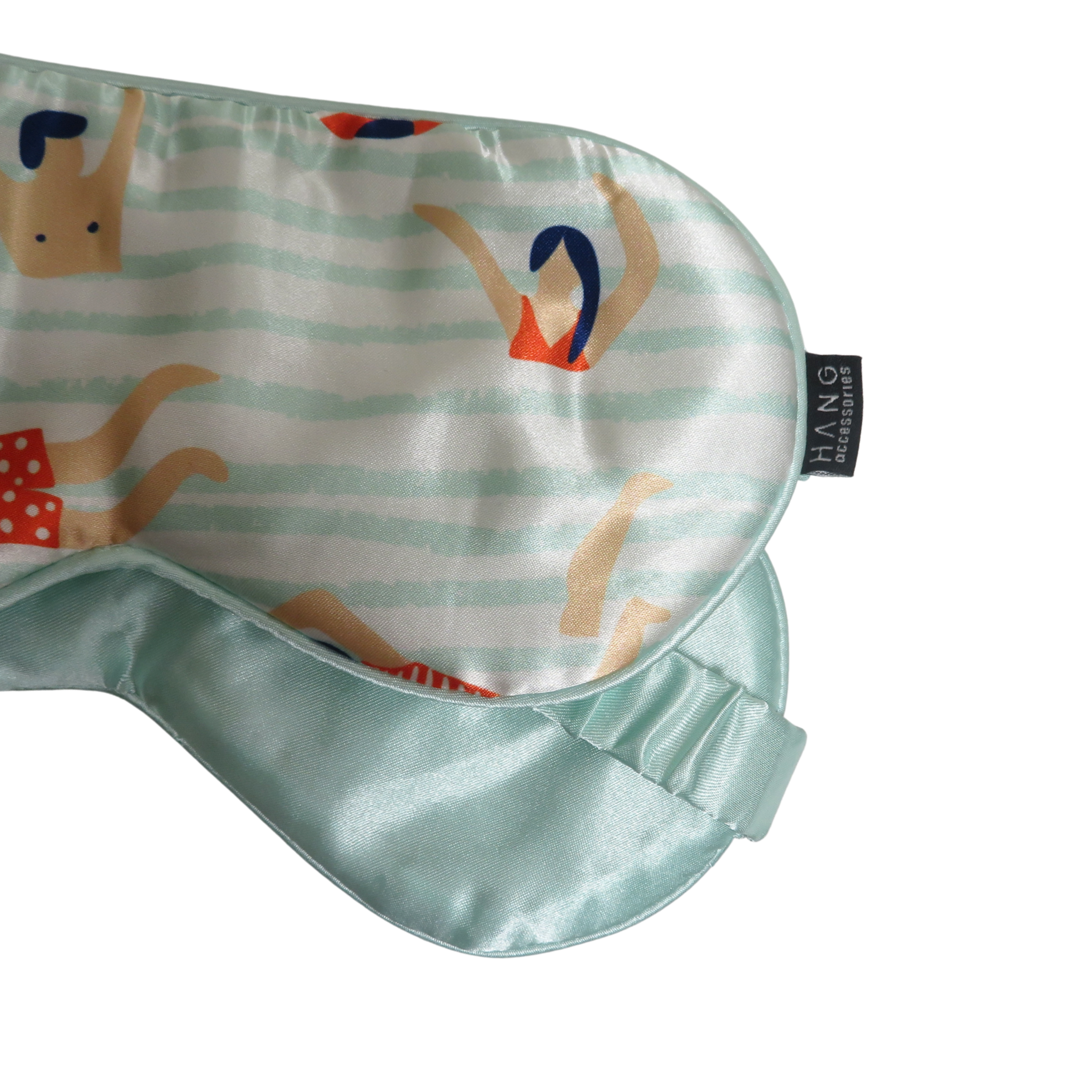 A close-up of a satin sleep mask with a mint green elasticized edge and a printed pattern of stylized figures on a white and mint striped.
