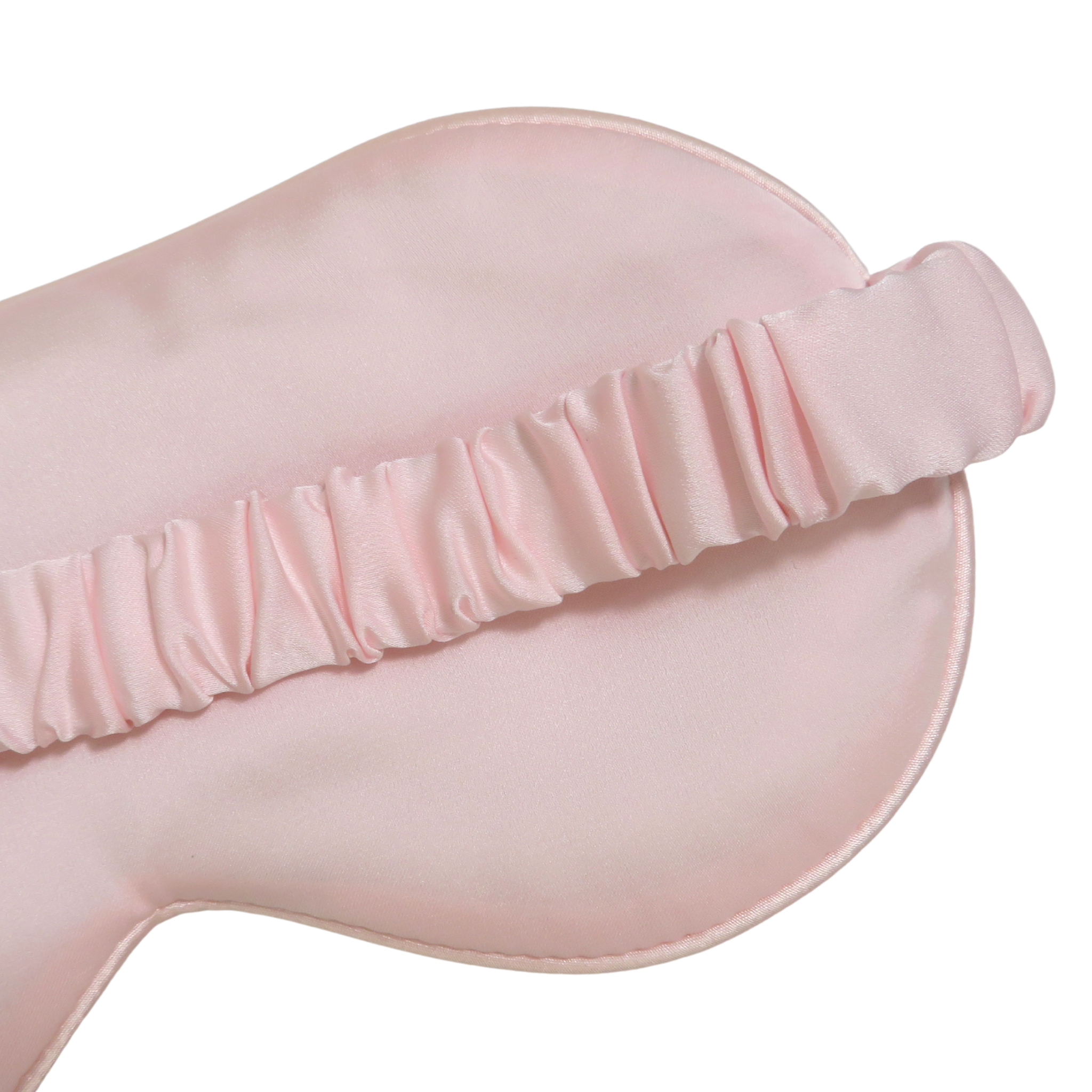 A close-up of a light pink satin sleep mask with a matching ruffled elastic strap, shown against a plain white background.