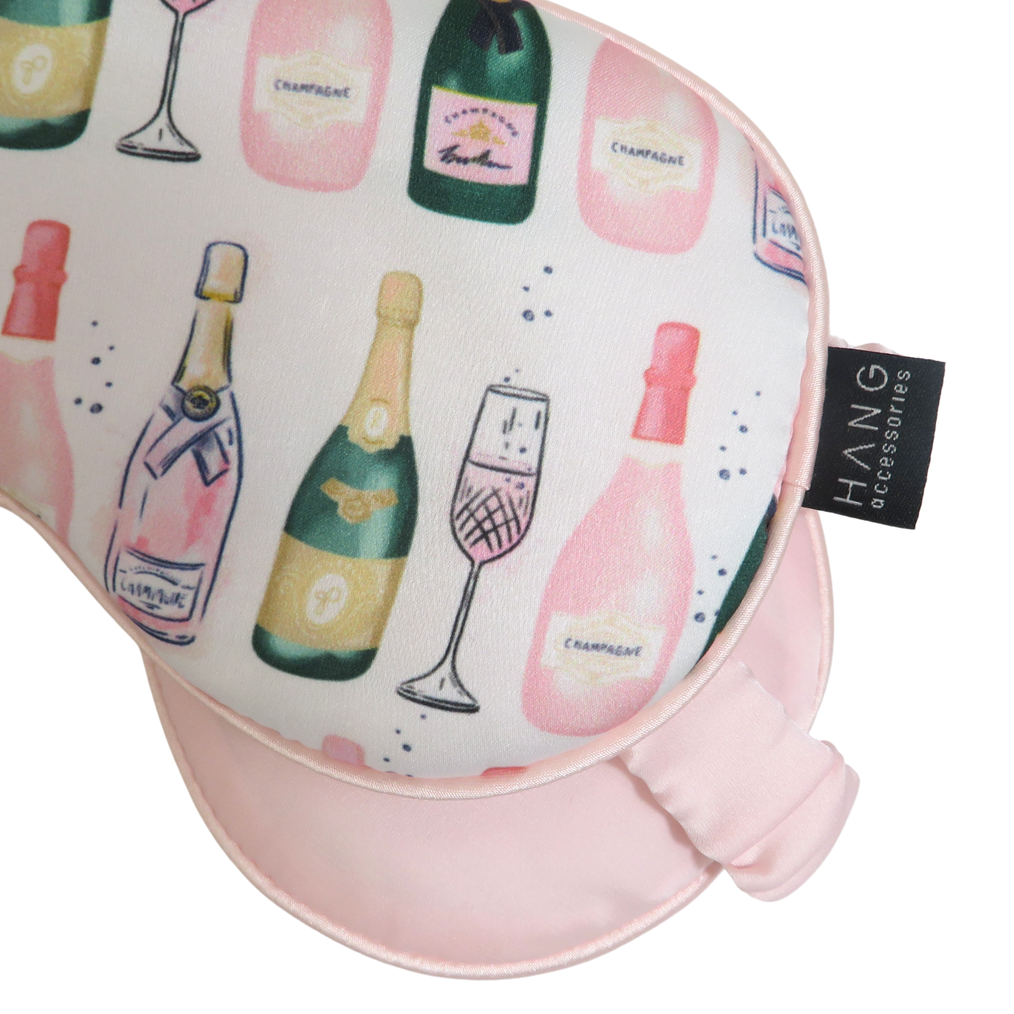 A sleep mask with a champagne bottle and glass pattern  and a pink eye mask with an elastic strap on a white background.