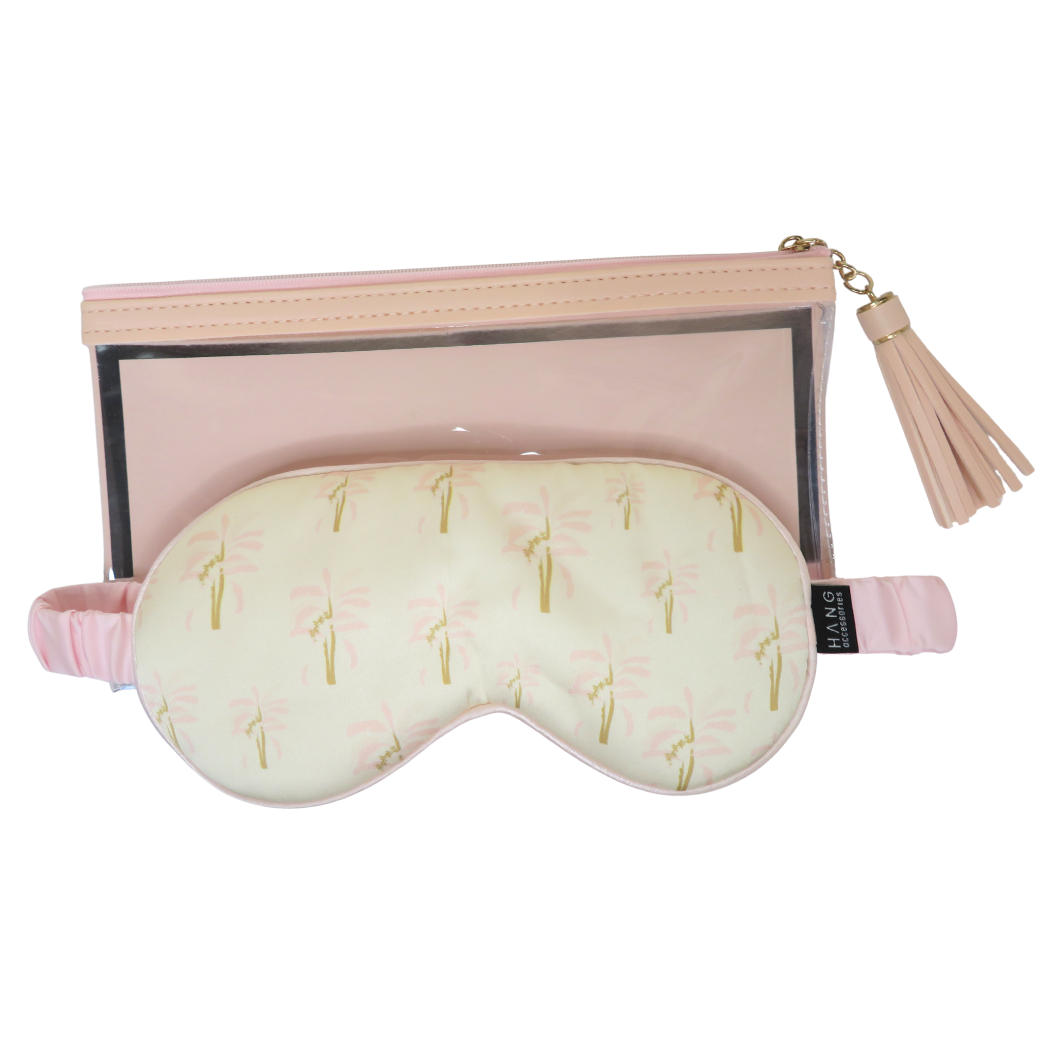 A travel set featuring a light pink zippered pouch with a clear window and tassel zipper pull, alongside a matching sleep mask with a pale yellow background and pink palm tree pattern.